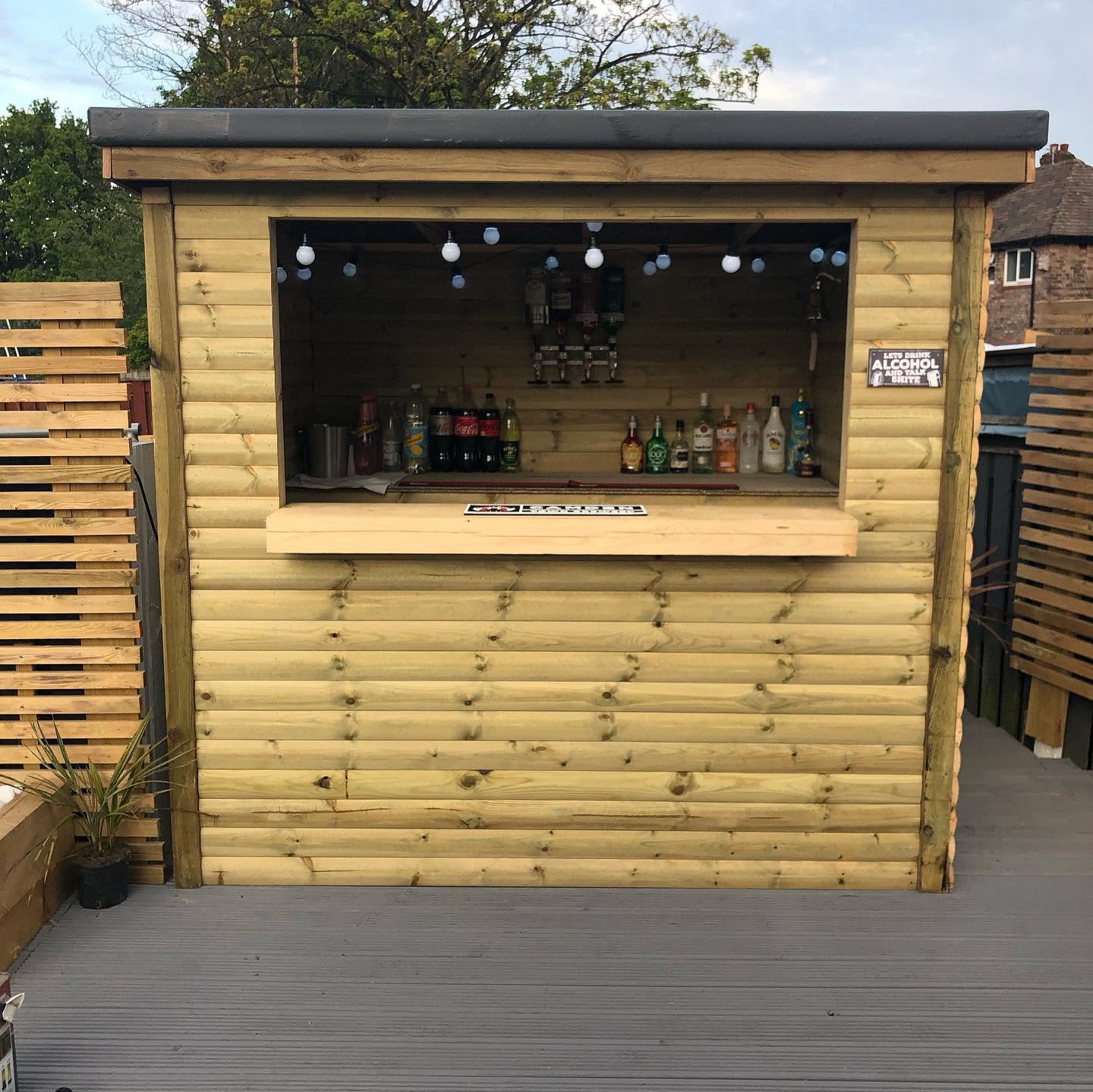 Garden bar lit at twilight — landscaping and joinery by RG