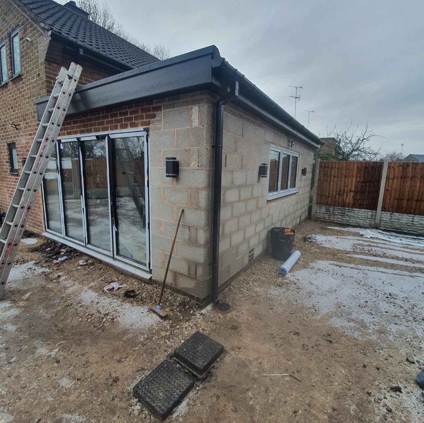 Single-storey rendered rear extension under construction with bi-fold opening